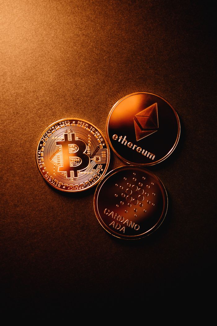 services-05 Close-up of Bitcoin, Ethereum, and Cardano coins arranged on a metallic copper background.