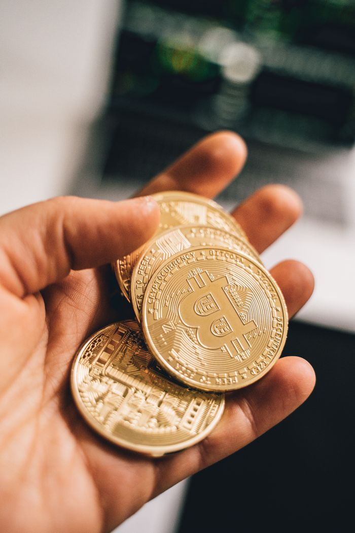 get-in-touch Close-up of a hand holding multiple Bitcoin coins symbolizing digital currency and economic growth.